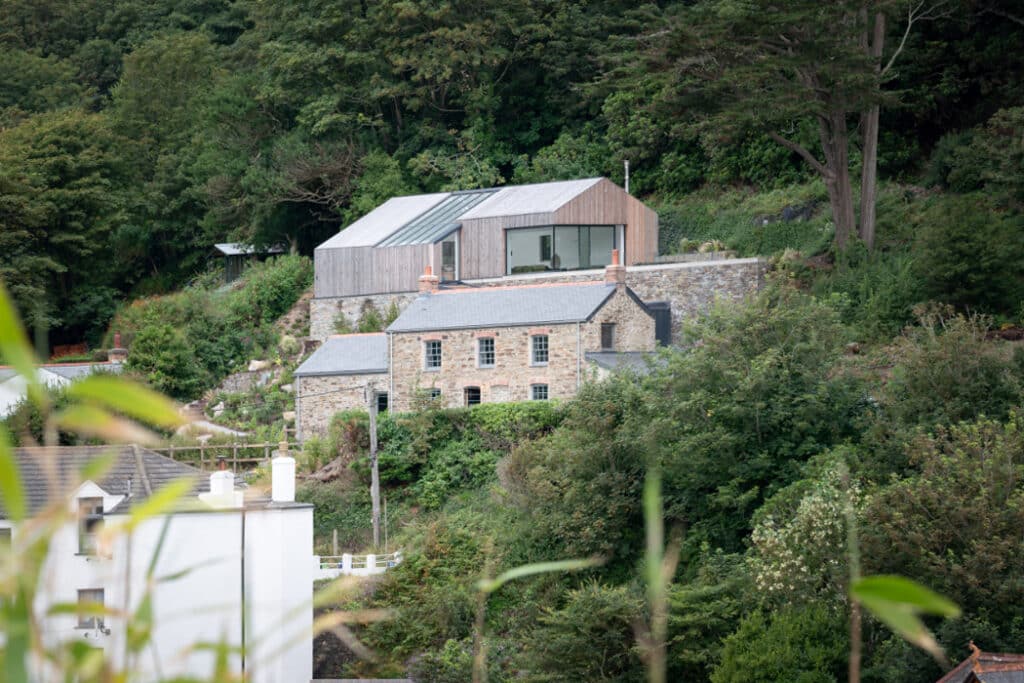 The modern extension sits on the slope above the traditional cottages
