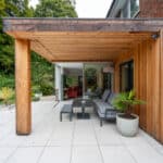 Thumbnail of http://Wooden%20outdoor%20patio%20with%20seating%20area,%20modern%20design.%20Surrounded%20by%20potted%20plants%20and%20trees,%20leading%20into%20a%20house%20with%20glass%20doors.