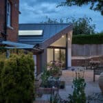 Thumbnail of http://Modern%20extension%20with%20large%20glass%20sliding%20doors%20attached%20to%20a%20brick%20building,%20surrounded%20by%20a%20garden%20patio%20with%20plants%20and%20outdoor%20furniture,%20under%20a%20twilight%20sky.