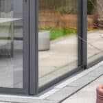 Thumbnail of http://Glass%20doors%20open%20to%20a%20patio%20with%20concrete%20tiles,%20a%20potted%20plant%20in%20the%20foreground,%20and%20a%20wooden%20planter%20with%20greenery%20in%20the%20background.