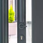 Thumbnail of http://A%20modern%20grey%20door%20is%20partially%20open,%20showing%20its%20handle%20and%20lock,%20with%20a%20potted%20plant%20visible%20outside%20in%20the%20background.