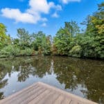 Thumbnail of http://A%20wooden%20decking%20overlooks%20a%20calm%20pond%20surrounded%20by%20dense%20green%20trees%20under%20a%20blue%20sky%20with%20scattered%20clouds.