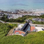 Thumbnail of http://Aerial%20view%20of%20a%20modern%20house%20on%20a%20hillside%20with%20a%20sloping%20roof,%20overlooking%20a%20beach,%20sea,%20car%20park,%20road,%20and%20surrounding%20greenery.