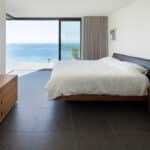 Thumbnail of http://Modern%20bedroom%20with%20a%20large%20bed,%20wooden%20furniture,%20tiled%20floor,%20and%20floor-to-ceiling%20glass%20doors%20opening%20to%20a%20balcony%20with%20a%20sea%20view.