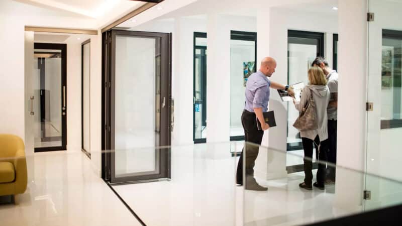 Sunflex UK distributor meeting with customers in a modern showroom displaying bifold and sliding door systems.