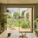Thumbnail of http://Sunflex%20bifold%20doors%20opening%20from%20modern%20eco-home%20kitchen%20to%20garden%20courtyard%20with%20stone%20walls%20and%20planted%20beds.