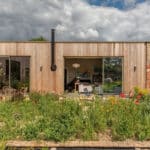 Thumbnail of http://Modern%20timber-clad%20eco-home%20with%20large%20sliding%20glass%20doors%20opening%20onto%20a%20wildflower%20garden
