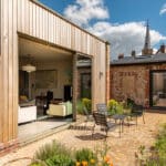 Thumbnail of http://Modern%20bifold%20doors%20opening%20onto%20paved%20courtyard%20with%20seating%20area,%20brick%20building%20and%20church%20spire%20visible%20beyond.