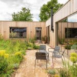 Thumbnail of http://Modern%20timber-clad%20Suffolk%20eco-home%20with%20large%20bifold%20doors%20opening%20onto%20paved%20courtyard%20garden%20with%20seating.