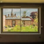 Thumbnail of http://Large%20sliding%20doors%20with%20garden%20view%20from%20contemporary%20Suffolk%20eco-home%20interior,%20showing%20manicured%20garden%20and%20period%20architecture%20beyond.