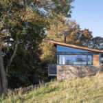 Thumbnail of http://Rescobie%20Pavilion%20with%20large%20glazed%20sliding%20doors%20framing%20Scottish%20landscape%20views,%20featuring%20timber%20cladding%20and%20stone%20base.